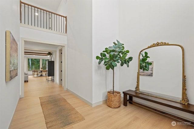 hallway featuring a towering ceiling and light wood-type flooring