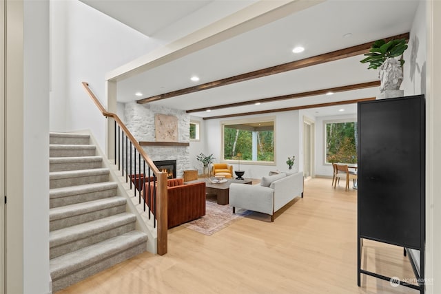 living room featuring light wood-type flooring, a fireplace, and beam ceiling