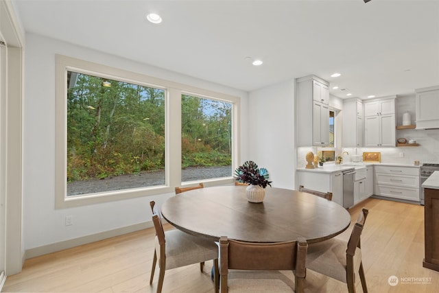 dining space with sink and light wood-type flooring