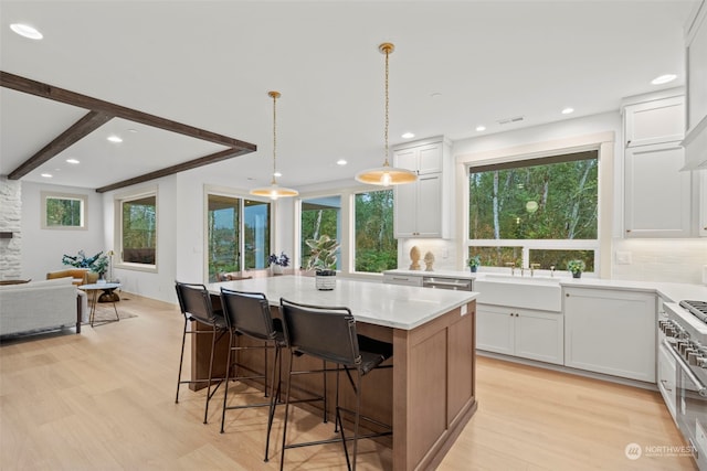 kitchen with decorative backsplash, light hardwood / wood-style floors, white cabinets, and a kitchen island