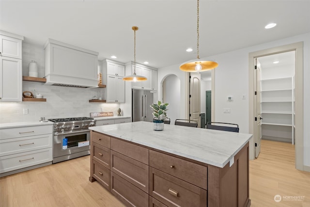 kitchen with hanging light fixtures, white cabinetry, backsplash, and premium appliances