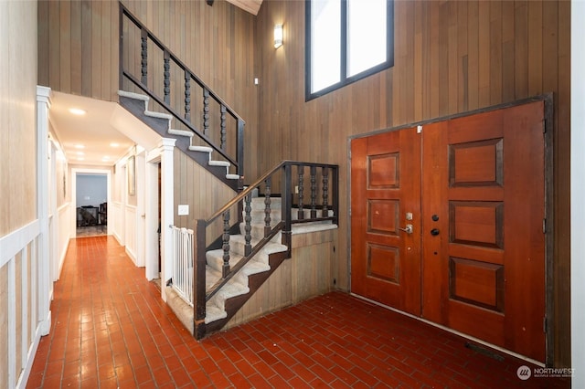 foyer with a towering ceiling and wood walls