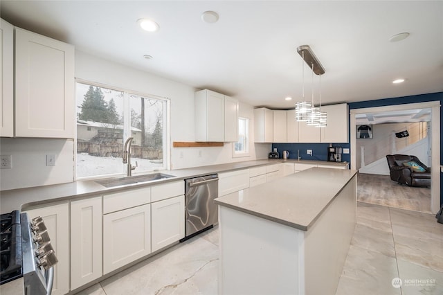 kitchen with sink, decorative light fixtures, appliances with stainless steel finishes, a kitchen island, and white cabinets