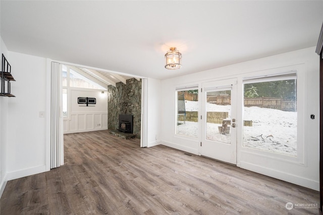 interior space with vaulted ceiling with beams, plenty of natural light, hardwood / wood-style flooring, and a wood stove