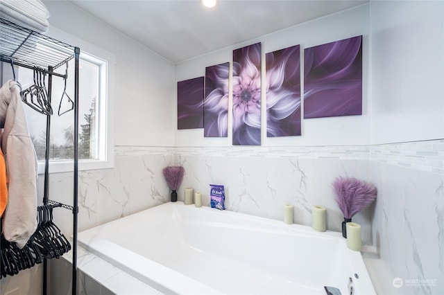 bathroom with a relaxing tiled tub and plenty of natural light