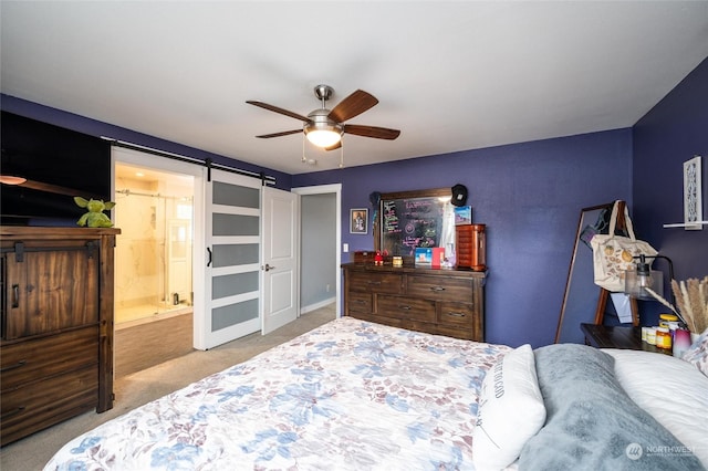 bedroom with light colored carpet, a barn door, ceiling fan, and ensuite bathroom