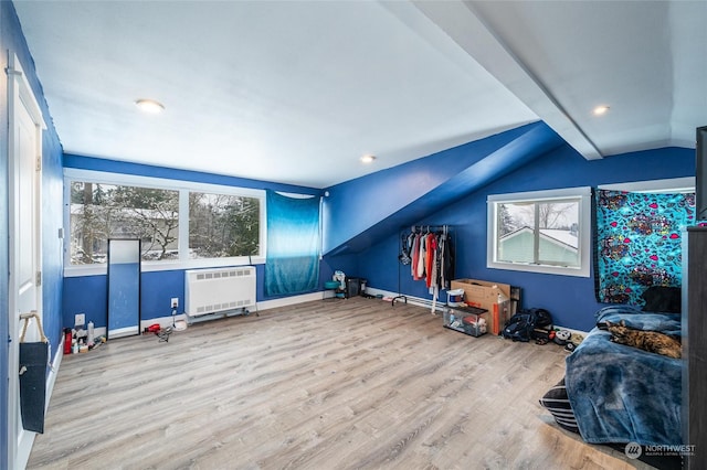 interior space featuring lofted ceiling, radiator, hardwood / wood-style flooring, and plenty of natural light