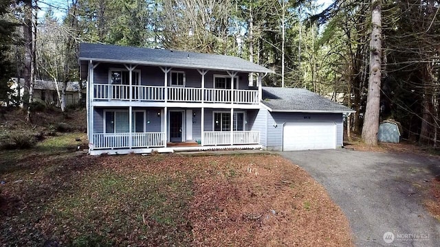 view of front of home featuring a balcony, aphalt driveway, a garage, and a porch