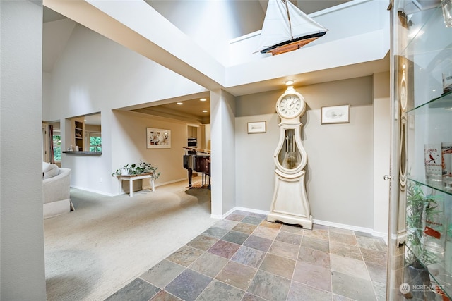 carpeted entryway with a towering ceiling