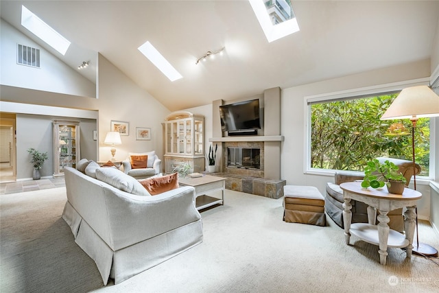 living room with a healthy amount of sunlight, lofted ceiling with skylight, light carpet, and a tile fireplace