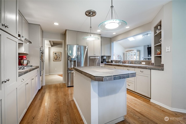 kitchen featuring pendant lighting, lofted ceiling, a center island, light hardwood / wood-style floors, and stainless steel appliances