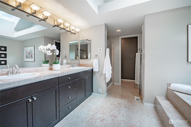 bathroom with a shower with door, vanity, and a skylight