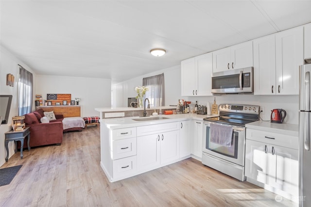 kitchen featuring sink, white cabinets, kitchen peninsula, stainless steel appliances, and light wood-type flooring