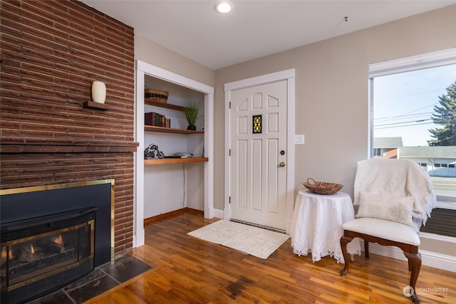 entrance foyer with dark hardwood / wood-style flooring and a brick fireplace