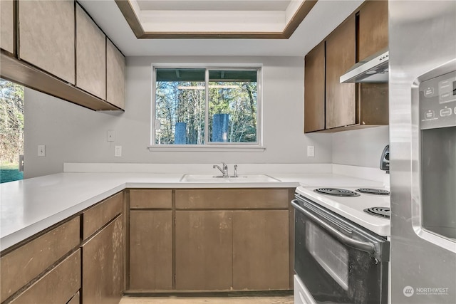 kitchen featuring a raised ceiling, stainless steel refrigerator with ice dispenser, sink, and white electric stove