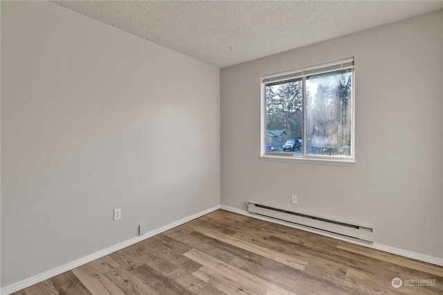 unfurnished room featuring baseboard heating, a textured ceiling, and light wood-type flooring