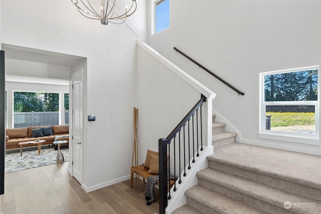 stairs featuring hardwood / wood-style flooring, an inviting chandelier, and a high ceiling