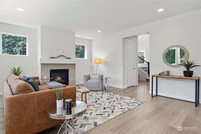 living room featuring a tiled fireplace and light hardwood / wood-style floors