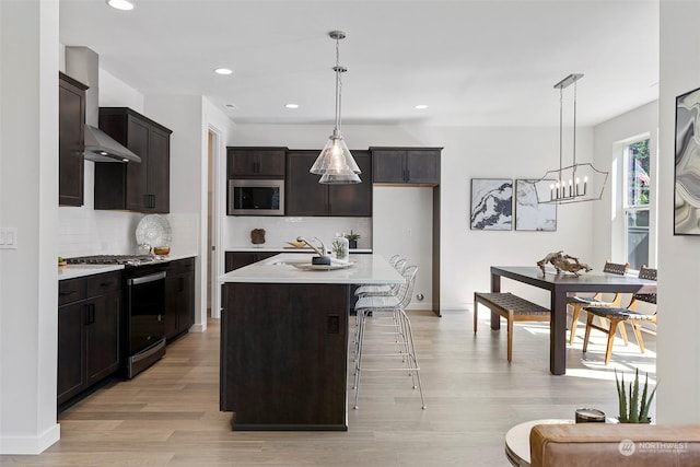 kitchen featuring decorative backsplash, appliances with stainless steel finishes, decorative light fixtures, and a kitchen island