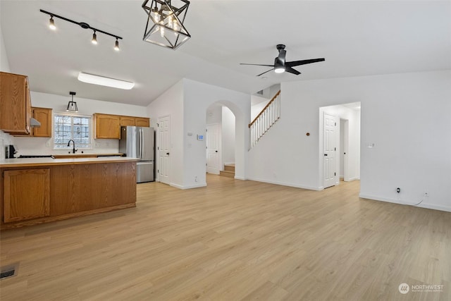 kitchen with lofted ceiling, light wood-type flooring, stainless steel refrigerator, pendant lighting, and ceiling fan