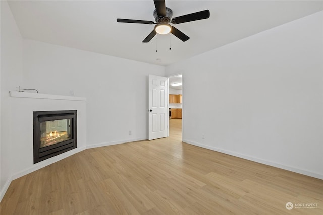 unfurnished living room with a multi sided fireplace, ceiling fan, and light hardwood / wood-style floors