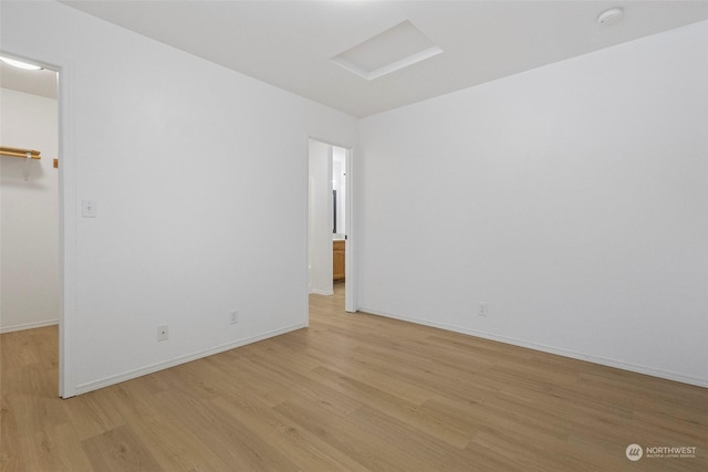 unfurnished bedroom featuring a walk in closet, light hardwood / wood-style floors, and a closet