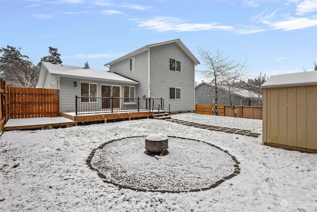 snow covered back of property featuring a wooden deck and a fire pit