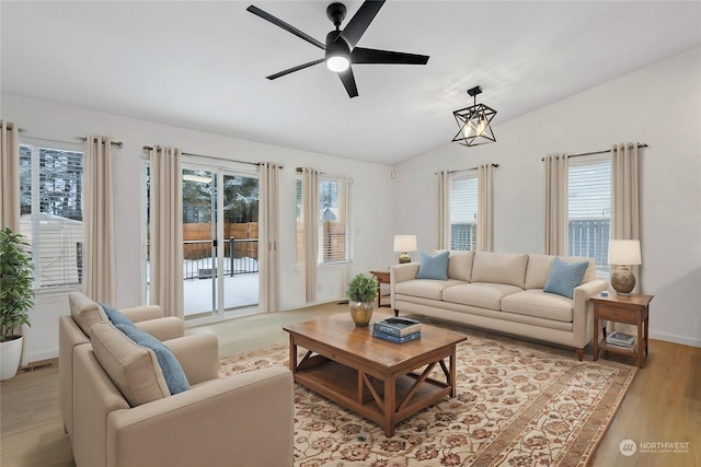 living room with vaulted ceiling, a healthy amount of sunlight, and light hardwood / wood-style flooring