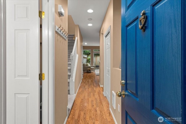 hallway with light wood-style flooring, stairs, baseboards, and recessed lighting