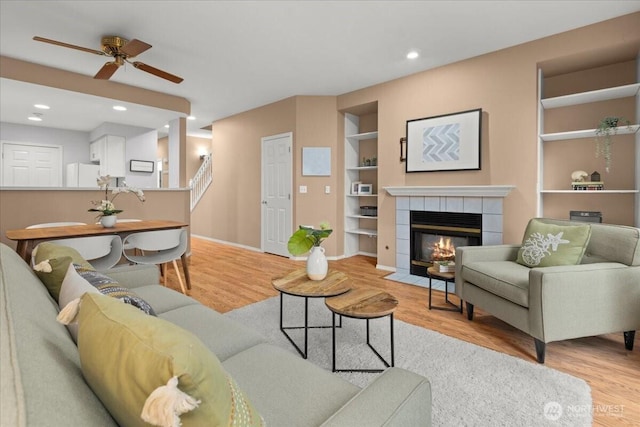 living area with baseboards, built in features, light wood-type flooring, a fireplace, and recessed lighting