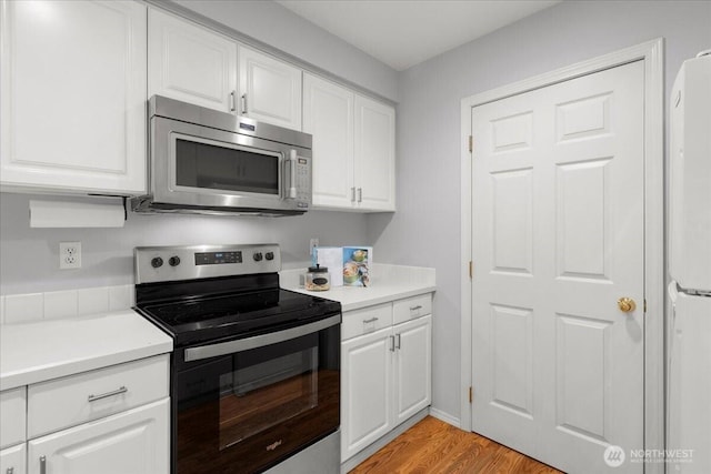 kitchen with light wood-style floors, white cabinetry, appliances with stainless steel finishes, and light countertops