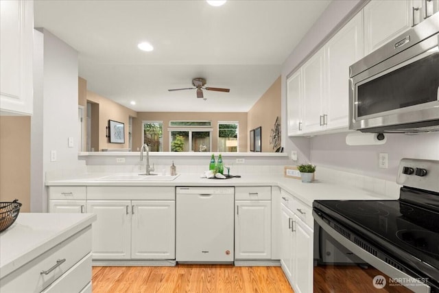 kitchen featuring light countertops, appliances with stainless steel finishes, a sink, and white cabinetry