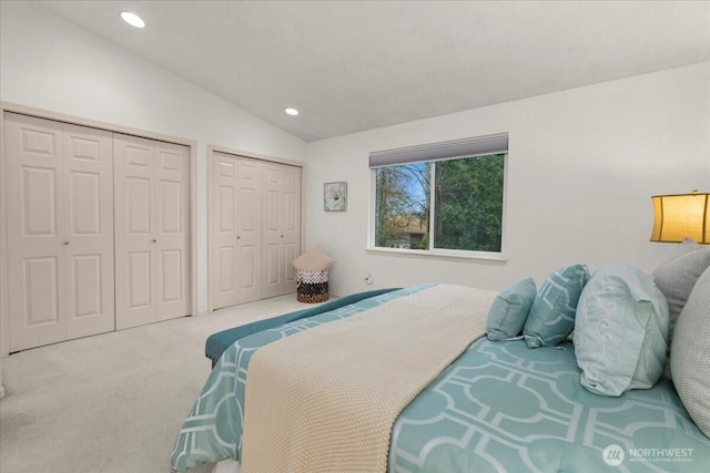 carpeted bedroom featuring lofted ceiling, recessed lighting, and multiple closets