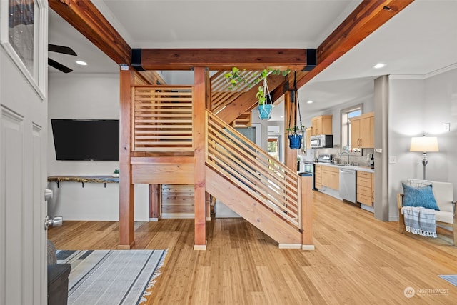 staircase featuring ornamental molding, wood-type flooring, and sink