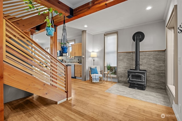 unfurnished living room featuring sink, ornamental molding, light hardwood / wood-style floors, and a wood stove