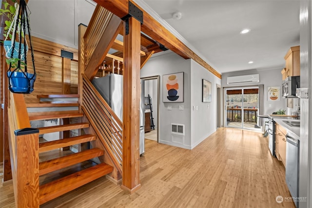 stairs with ornamental molding, sink, hardwood / wood-style floors, and a wall unit AC