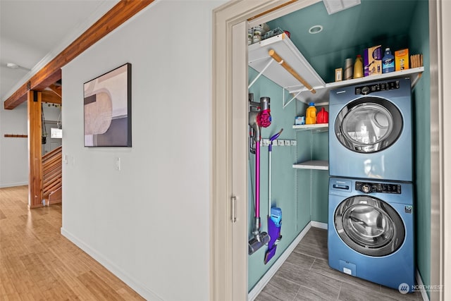 clothes washing area featuring stacked washer and clothes dryer and hardwood / wood-style floors