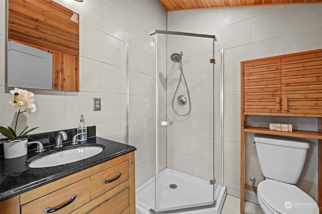 bathroom with tile walls, vanity, toilet, and walk in shower