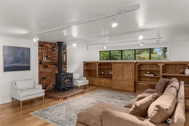 living room featuring a wood stove, track lighting, and light wood-type flooring