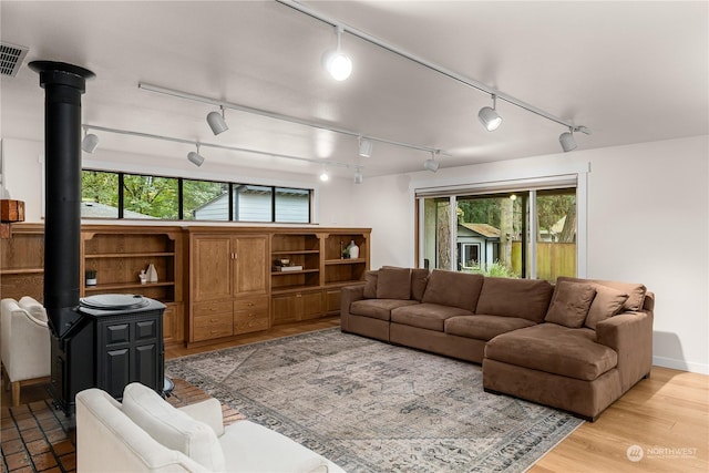 living room with track lighting, a healthy amount of sunlight, and a wood stove