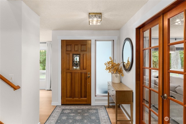 foyer entrance with a textured ceiling and light wood-type flooring