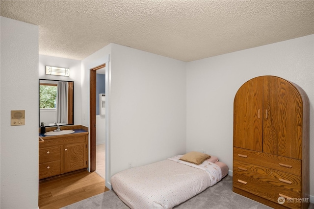 bedroom featuring sink, a textured ceiling, and light wood-type flooring