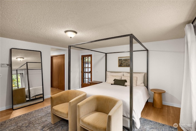 bedroom featuring hardwood / wood-style floors, multiple windows, and a textured ceiling