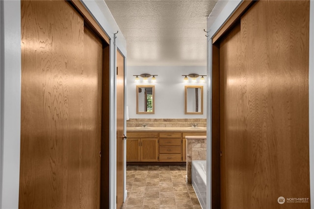 bathroom with vanity, a bathtub, and a textured ceiling