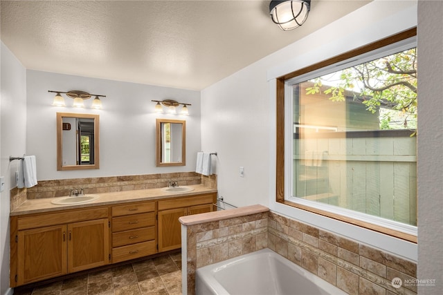 bathroom with vanity, a textured ceiling, and a tub to relax in