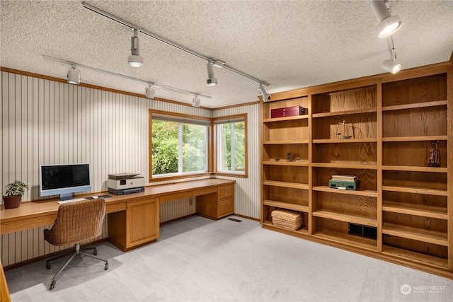 office space featuring radiator heating unit, built in desk, light carpet, and a textured ceiling