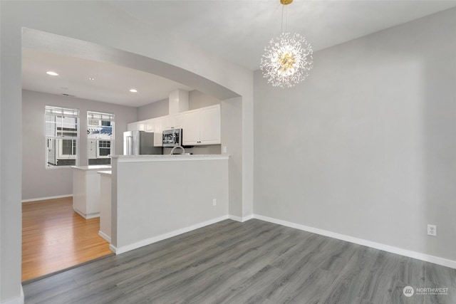 kitchen featuring hanging light fixtures, white cabinetry, appliances with stainless steel finishes, and kitchen peninsula