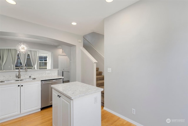 kitchen featuring sink, white cabinetry, a center island, decorative light fixtures, and stainless steel dishwasher