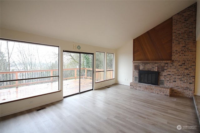 unfurnished living room featuring vaulted ceiling, a fireplace, and light hardwood / wood-style floors