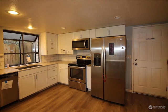 kitchen with stainless steel appliances, sink, light hardwood / wood-style flooring, and white cabinets